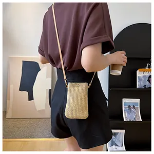 Detail of a hand-woven straw crossbody bag with herringbone texture and leather strap