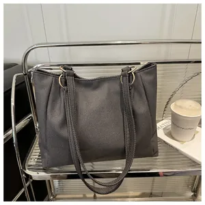 Detail of dark grey textured tote bag featuring silver metal rings and long shoulder straps