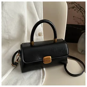 Close-up of black retro handbag featuring glossy texture and golden metal square lock