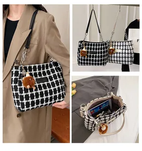 Detail of checkered tweed tote bag featuring chain straps, inner pockets and a plush bear