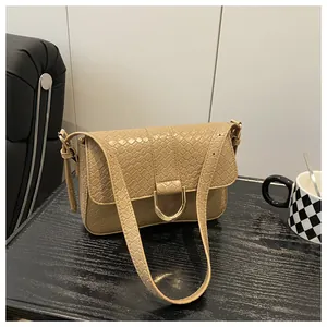 Detail of beige crocodile pattern leather handbag with gold D-ring buckle and shoulder strap
