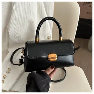 Close-up of black retro handbag with vintage texture and gold clasp on a white chair