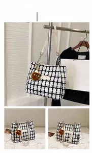 Detail of checkered tweed tote bag with light straps and a cute brown bear charm