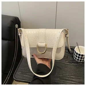 Detail of cream shoulder bag featuring woven texture and gold D-shaped buckle