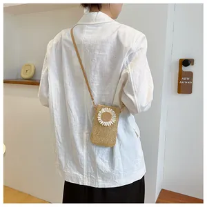 Detail of straw woven crossbody bag with sunflower decoration worn over a white linen blazer