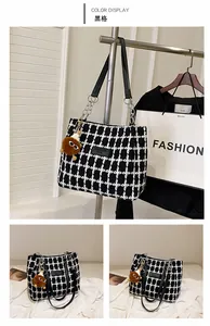 Detailed view of black grid wool tote bag with leather straps and plush charm