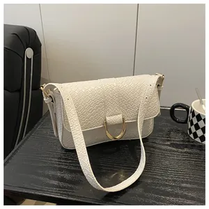 Close-up of cream crossbody bag featuring woven texture and golden horseshoe buckle