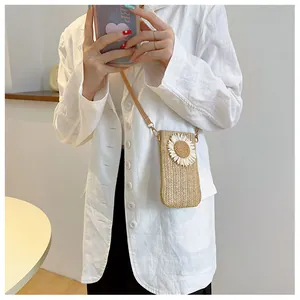 Detail of hand-woven straw crossbody bag with white daisy flower on white blazer outfit