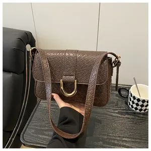 Detail of vintage brown embossed leather bag with golden D-ring buckle and croc texture