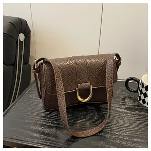 Close-up of vintage dark brown faux leather bag with crocodile pattern and golden U-buckle