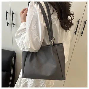 Detail of grey textured fabric tote bag with silver rings on white lace dress model