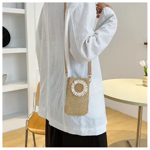 Straw crossbody bag with daisy floral detail shown on a model in a minimal setting