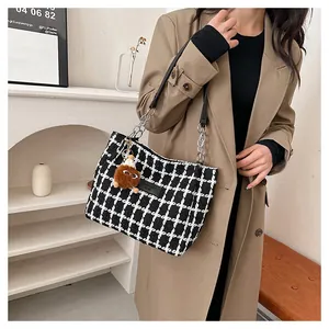 Close-up of houndstooth plaid tote bag with chain strap and plush pendant detail