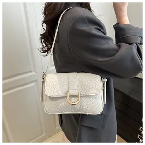 Detail of white woven leather shoulder bag with gold D-ring buckle on grey blazer