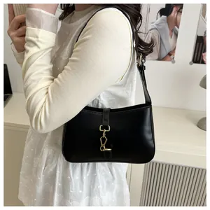 Detail of vintage black leather underarm bag featuring a prominent gold piston clasp closure