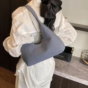 Blue-grey textured hobo bag with waffle pattern shown on shoulder in lifestyle setting