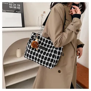 Detail of checkered tweed tote bag with chain strap and cute plush charm on coat