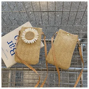 Detail of straw crossbody bag with daisy flower and magnetic snap closure in a cart