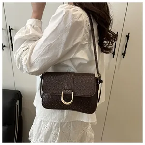 Detailed view of the dark brown crocodile embossed texture and golden metal buckle on the bag