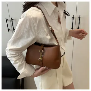 Detail of dark brown leather underarm bag with vintage gold piston lock closure
