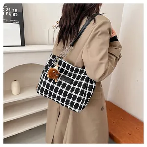 Detail of checkered woolen tote with leather chain strap and plush ball pendant charm