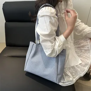 Minimalist light blue tote bag with metallic ring and denim-like texture for women
