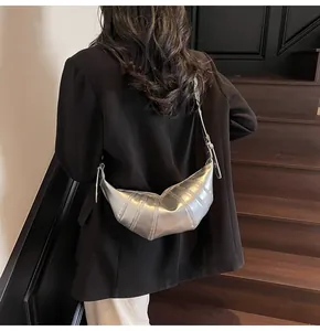 Detail of silver metallic croissant bag with quilted design worn over a black blazer