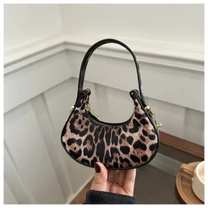 Détail d'un sac hobo léopard avec des finitions dorées et une fine bandoulière chic