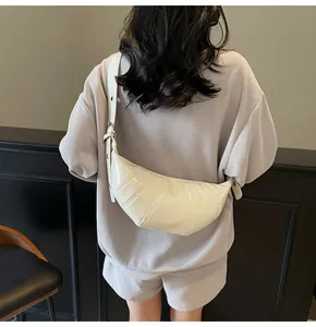 Detailed back view of a cream croissant bag with quilted glossy finish and wide strap