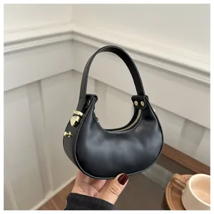 Détail du sac croissant noir avec quincaillerie dorée et texture en cuir lisse