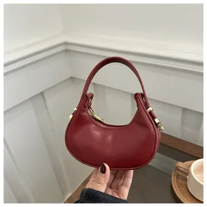 Détail du sac croissant bordeaux avec cuir lisse et fermeture éclair dorée élégante