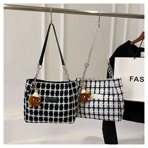 Detail of tweed tote bags with plaid patterns, chain straps and plush doll charms