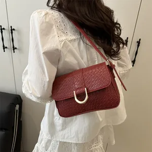 Deep red crocodile embossed crossbody bag with golden buckle shown on a model