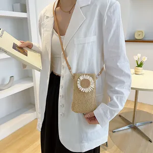 Fashionable straw crossbody bag with white daisy flower detail and brown shoulder strap