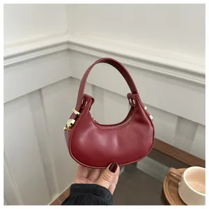 Détails du sac demi-lune bordeaux avec texture cuir et rivets métalliques dorés