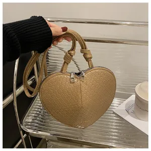 Detailed view of heart-shaped handbag with crocodile pattern and dual knotted handles