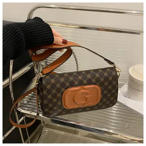 Close-up of vintage brown shoulder bag featuring gold floral prints and embossed G logo