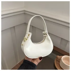 Détails du sac demi-lune blanc montrant les boucles dorées et la texture du cuir PU lisse