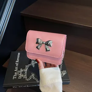Mini sac bandoulière rose avec nœud métallique sur fond d'escalier en bois sombre