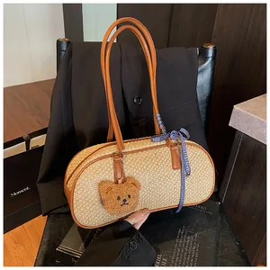 Détail du sac à main cylindrique en paille avec anses en cuir et charm d'ours mignon