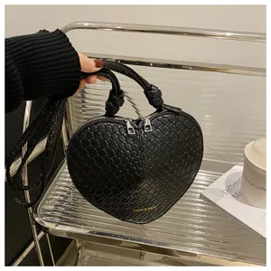 Macro detail of black heart-shaped woven handbag with silver zippers and tied handle decor
