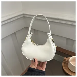 Détail d'un sac à main blanc minimaliste en forme de croissant avec finitions dorées
