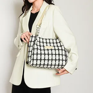 Classic black and white plaid tweed tote bag with chain strap shown on model in studio