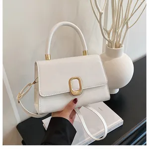 Detail of white leather handbag with golden oval clasp and minimalist top handle