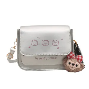 Silver matte crossbody bag with cartoon bear prints and a plush character charm
