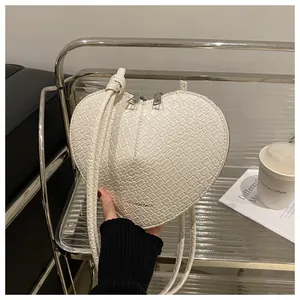 Detailed close-up of white heart-shaped woven leather bag with dual silver zippers
