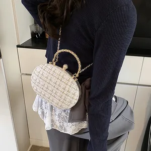 Elegant tweed evening bag with golden metal handle and chain strap worn by a model