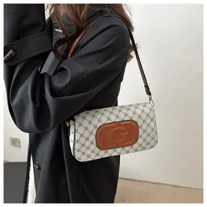 Detail of a vintage pattern shoulder bag with brown leather strap and G logo on a model