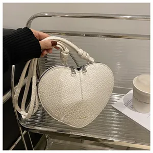 Detailed close-up of white heart-shaped bag with textured faux leather and top handles