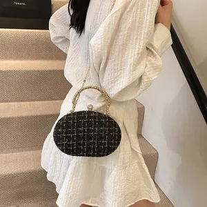 Elegant black and gold tweed evening clutch bag with round metal handle for formal events